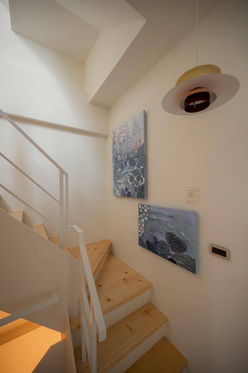 Blue-grey artworks and pendant light in the stairwell